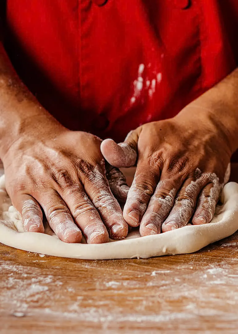 Pizza maker shaping fresh dough by hand