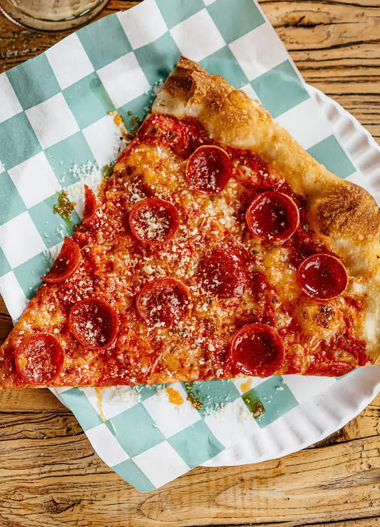 Large pepperoni pizza slice on checkered paper