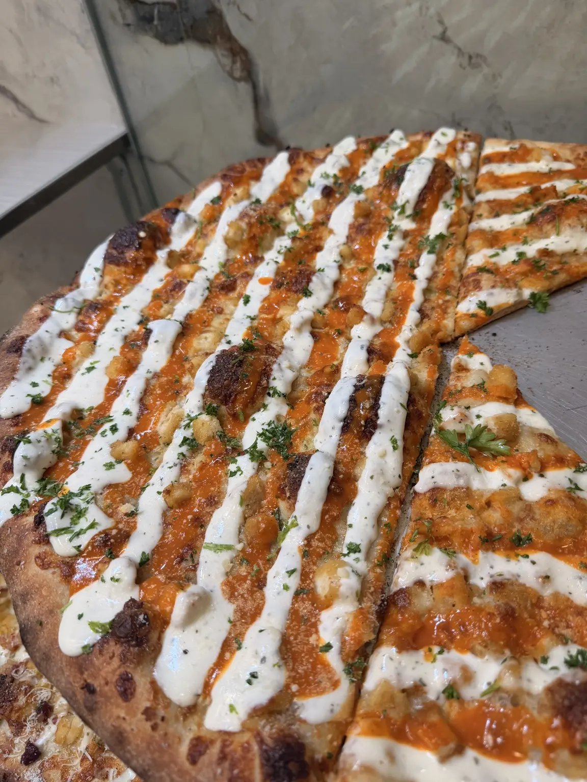 Close view of Buffalo chicken pizza with herbs and ranch