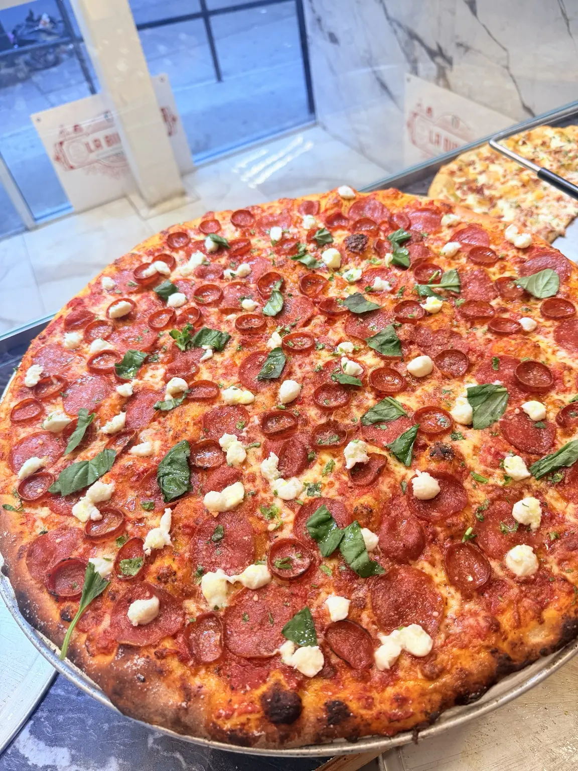 Pepperoni pizza finished with burrata and fresh basil