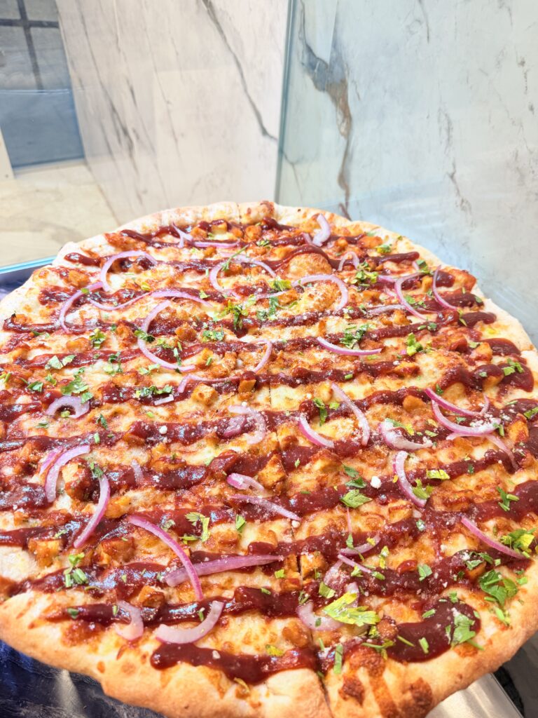 Loaded pizza with red onion, herbs, and savory toppings at La Bianca Pizza
