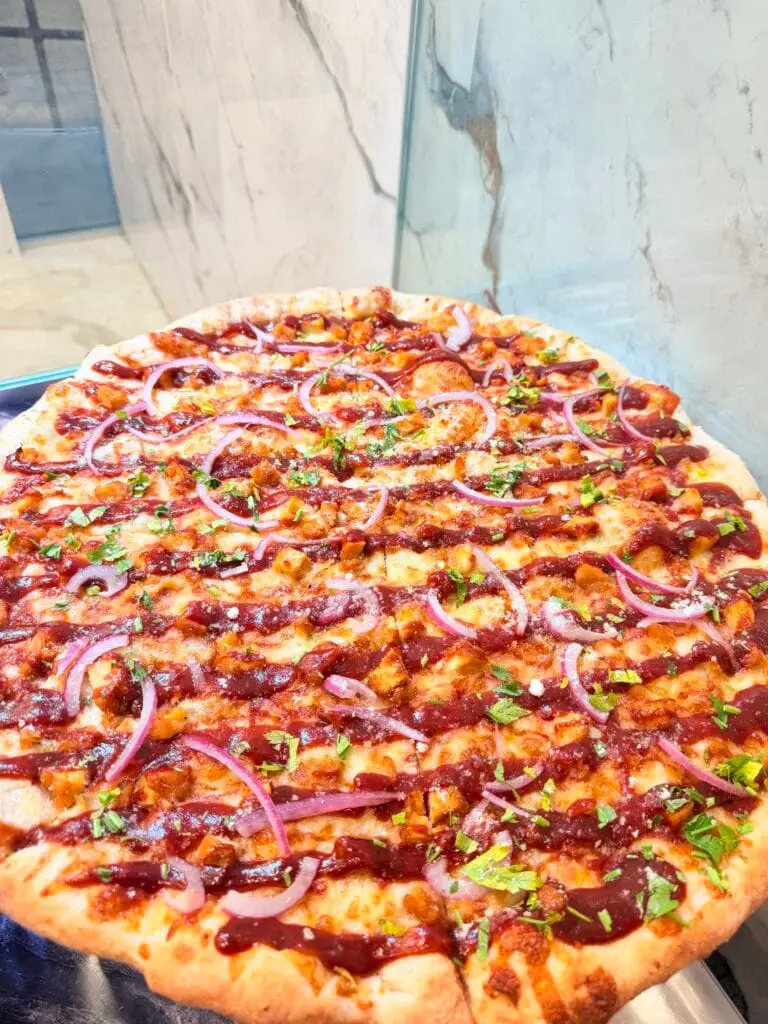 Loaded pizza with red onion, herbs, and savory toppings at La Bianca Pizza
